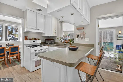 a kitchen with stainless steel appliances granite countertop a stove top oven a refrigerator a dining table and chairs with wooden floor