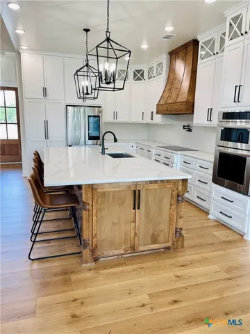 a kitchen with kitchen island granite countertop a sink a stove and a wooden floors