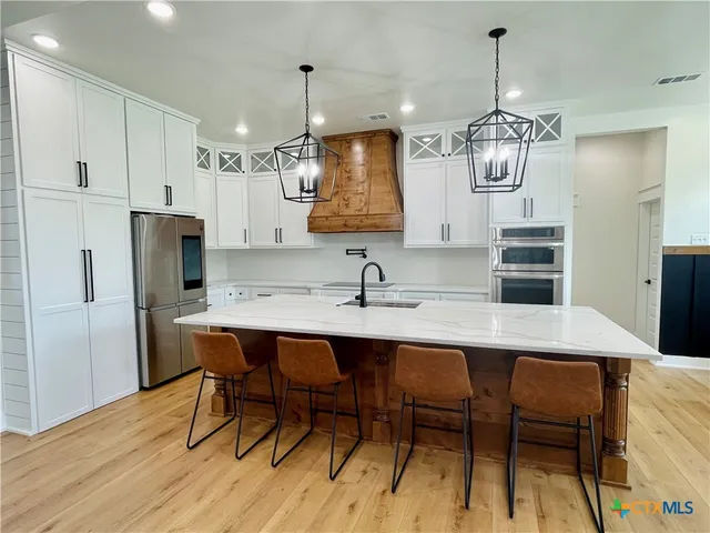 a kitchen with stainless steel appliances kitchen island a table and chairs in it