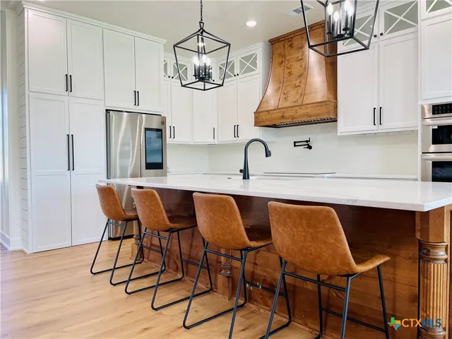 a kitchen with stainless steel appliances granite countertop a dining table chairs and sink