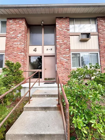 a view of a brick house with large windows and plants