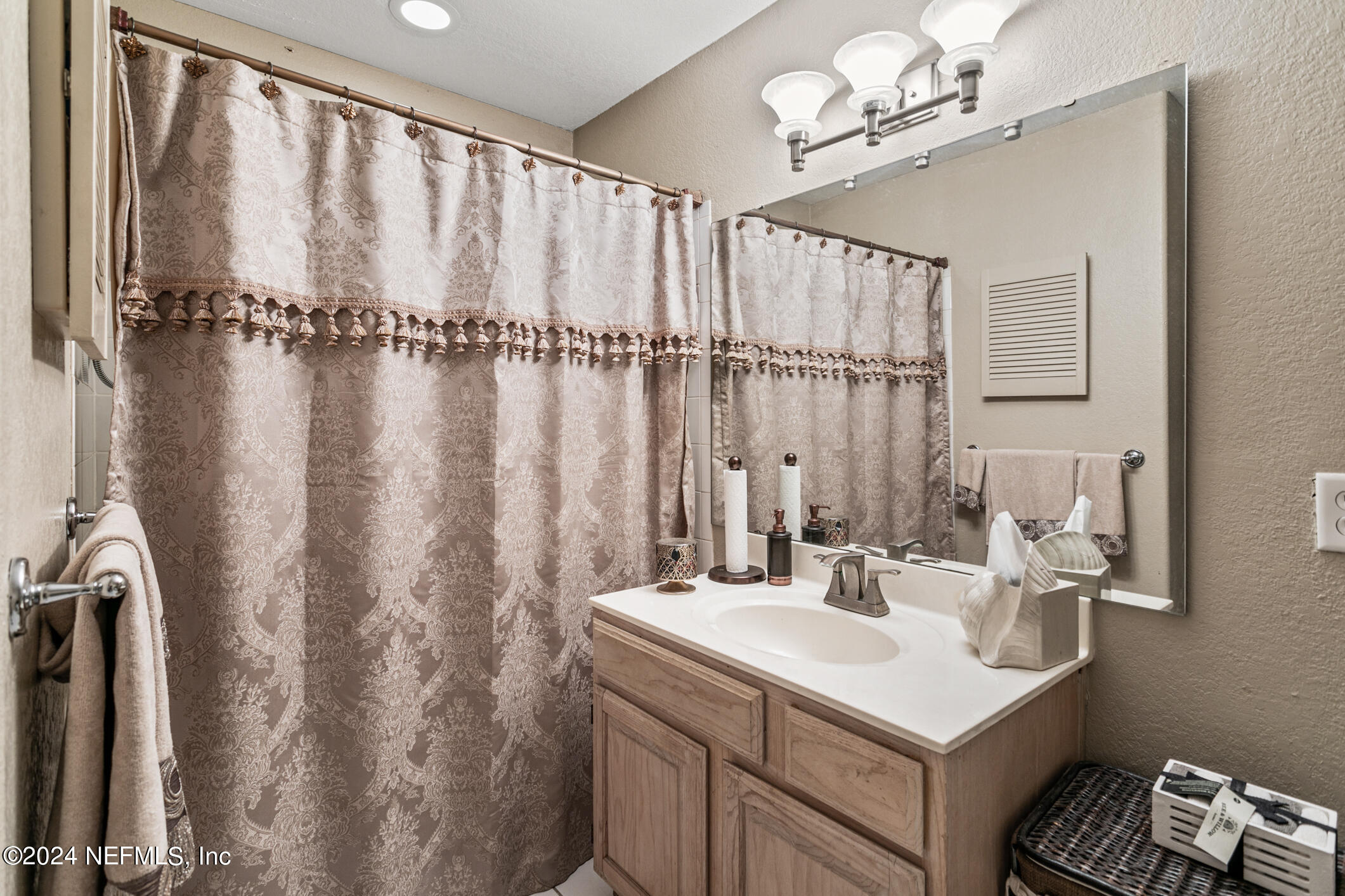 10150 Belle Rive Boulevard, Unit 2605 Jacksonville, FL 32256 - Photo 22 of 52 a bathroom with a sink a mirror and a shower curtain