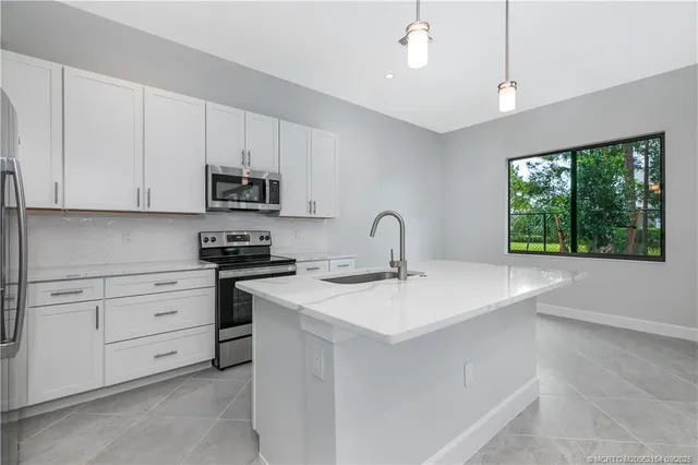 a kitchen with stainless steel appliances granite countertop a sink a stove and a refrigerator