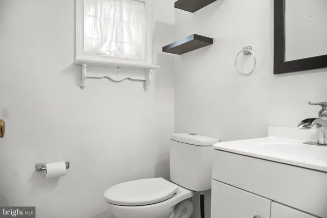 a bathroom with a toilet sink vanity and mirror