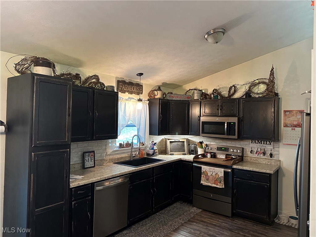 58440 Wharton Road Barnesville, OH 43713 - Photo 2 of 38 Kitchen featuring dark hardwood / wood-style floors, sink, hanging light fixtures, decorative backsplash, and stainless steel appliances