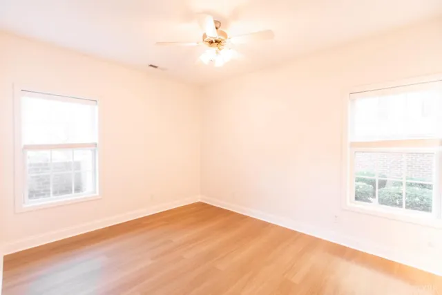 an empty room with a window and a ceiling fan