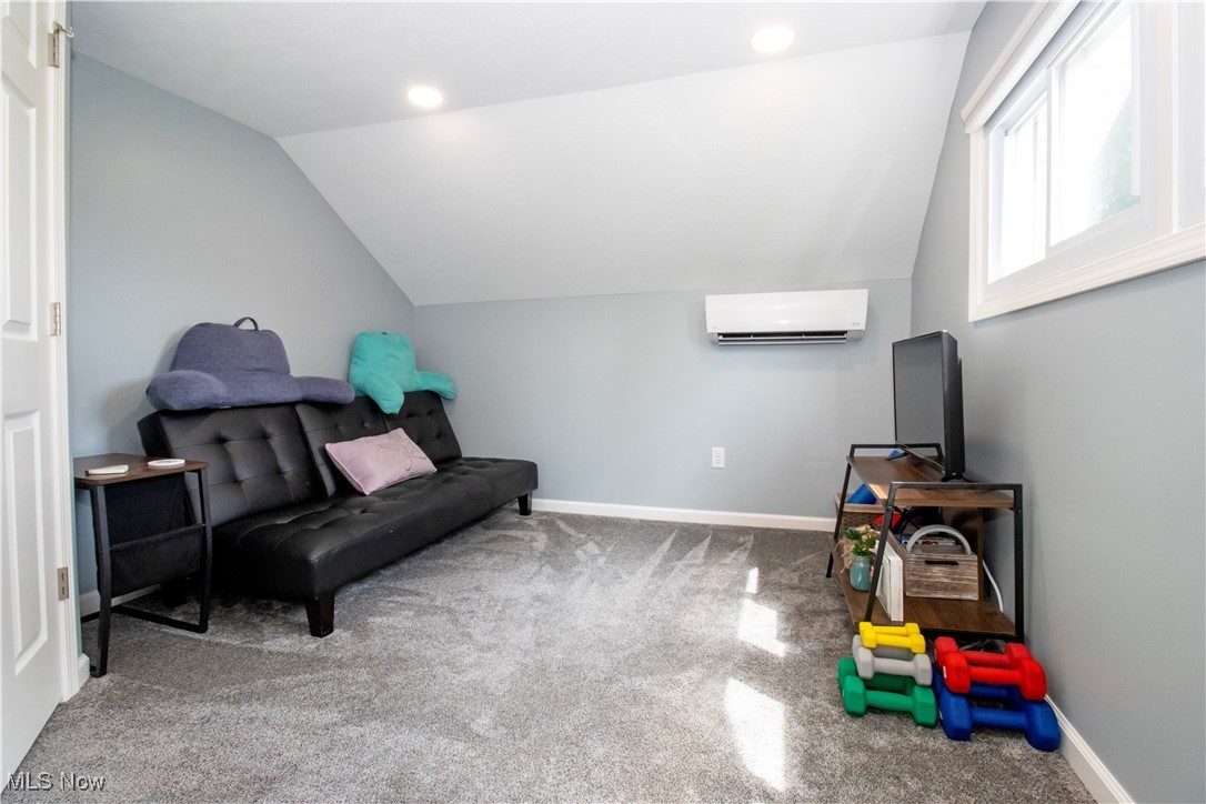 8984 Spencer Road Homerville, OH 44235 - Photo 25 of 27 Sitting room with a wall unit AC, carpet, and vaulted ceiling
