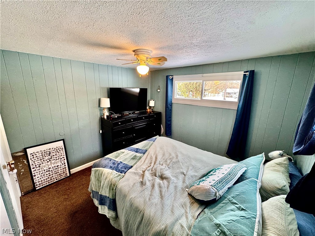 2852 Shelly Road Ravenna, OH 44266 - Photo 24 of 30 Bedroom featuring carpet floors, ceiling fan, wood walls, and a textured ceiling