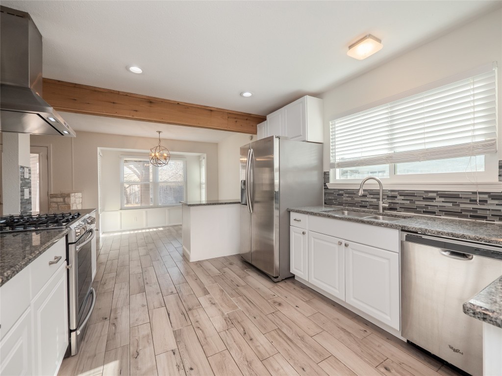 3209 Buffalo Springs Trail Georgetown, TX 78628 - Photo 11 of 32 a large kitchen with granite countertop a stove top oven a sink dishwasher a refrigerator and white cabinets with wooden floor