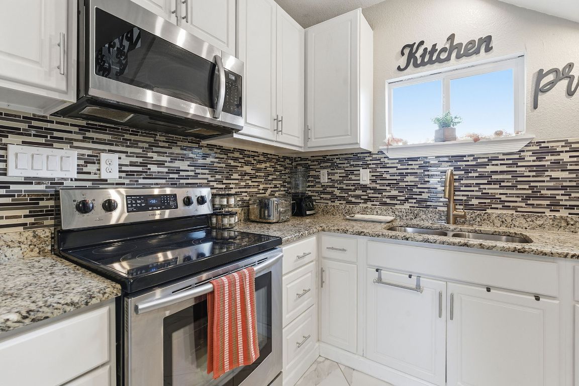 169 Ridgetop Road Buda, TX 78610 - Photo 3 of 40 a kitchen with stainless steel appliances granite countertop a stove a sink and a microwave