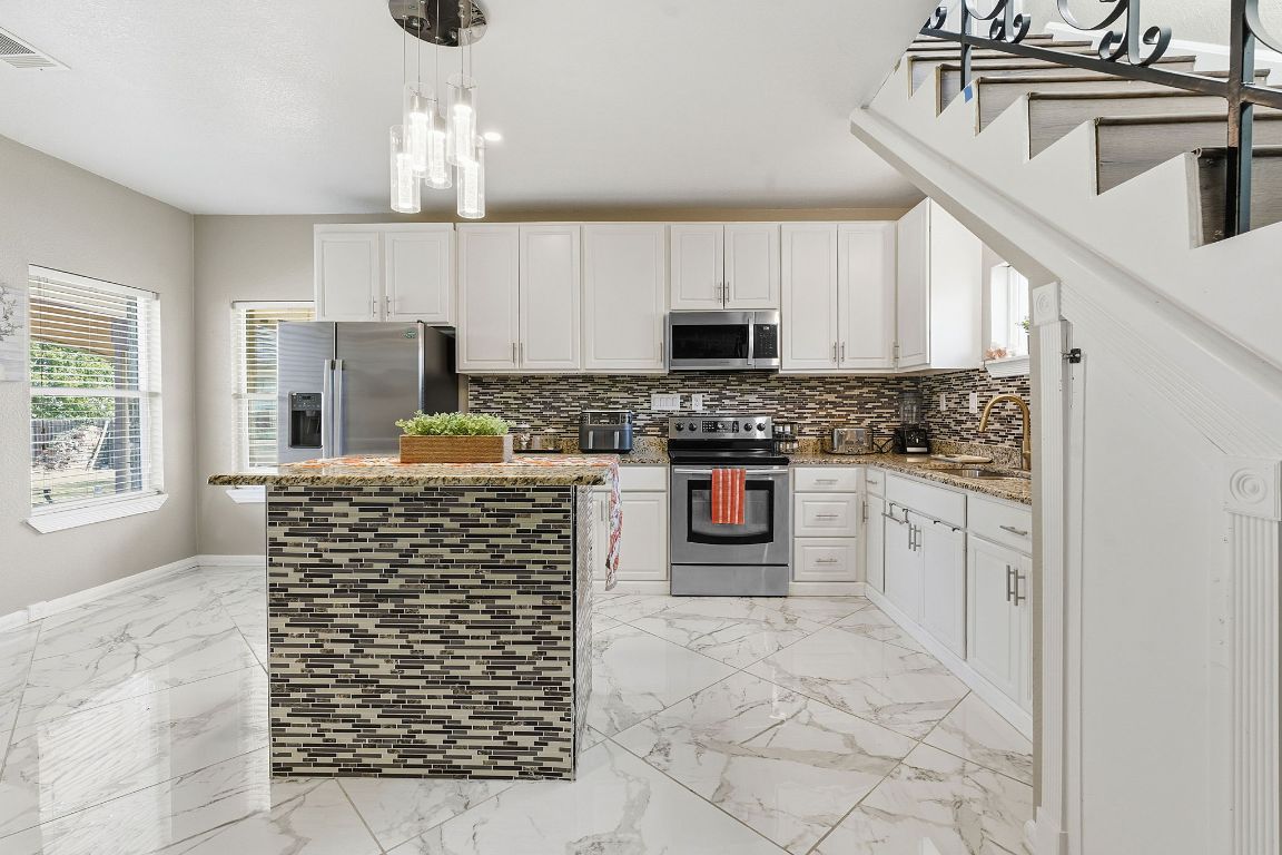 169 Ridgetop Road Buda, TX 78610 - Photo 4 of 40 a kitchen with stainless steel appliances granite countertop a stove sink microwave and cabinets
