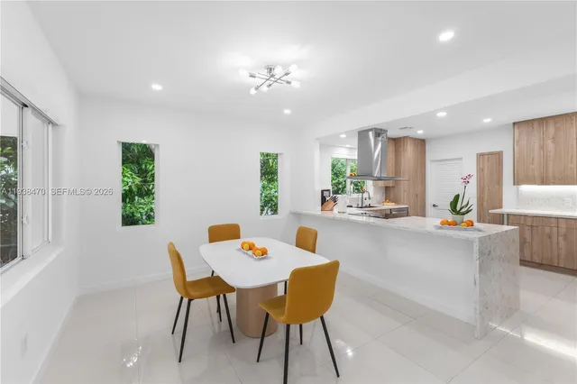 a dining room with a table chairs and a dining table with kitchen view