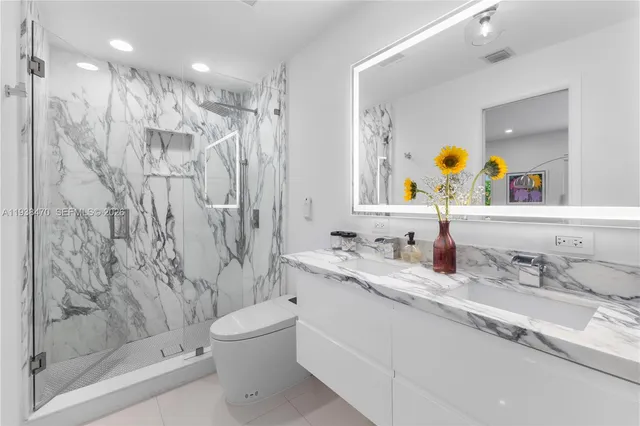 a bathroom with a granite countertop sink mirror vanity and toilet