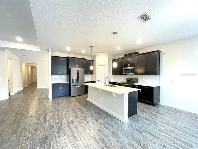 a large kitchen with stainless steel appliances kitchen island a large counter top and a wooden floors