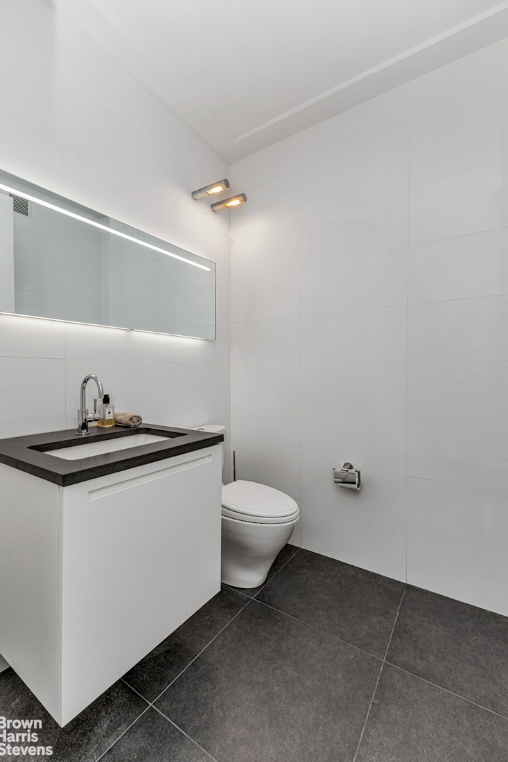 151 East 58th Street, Unit 43E Manhattan, NY 10022 - Photo 19 of 50 a white toilet sitting next to a bathroom sink
