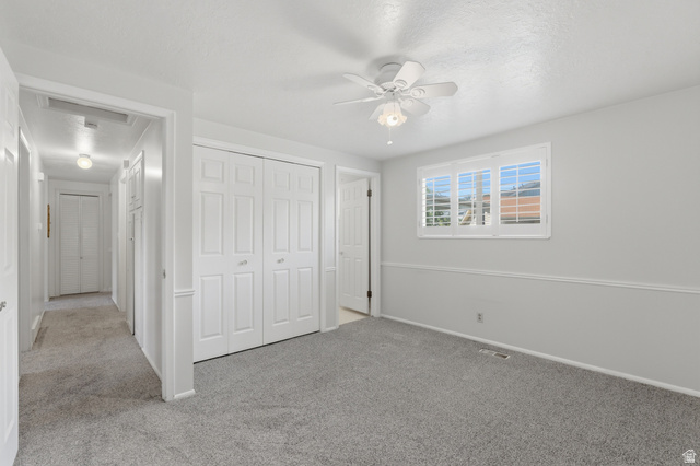 148 Tennyson Avenue Sandy, UT 84070 - Photo 20 of 55 Carpeted interior space featuring white walls and trim, a multi-panel window with white shutters, and a ceiling fan with light fixture