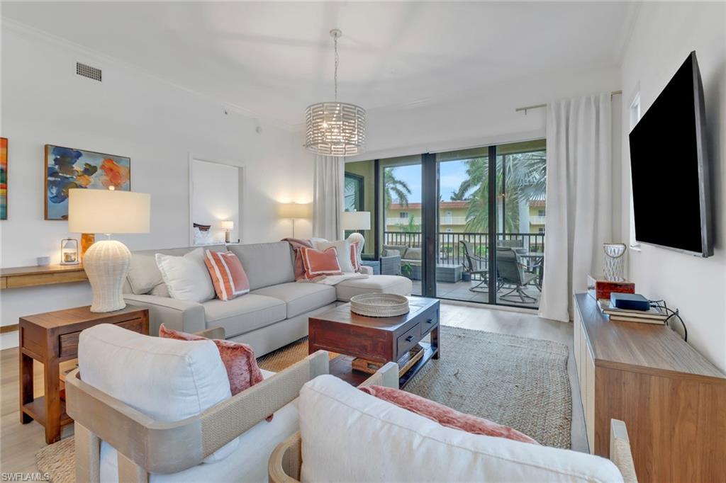 985 Sandpiper Street, Unit I204 Naples, FL 34102 - Photo 6 of 45 a living room with furniture a flat screen tv and a floor to ceiling window