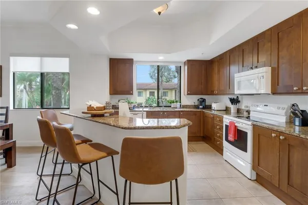 a kitchen with stainless steel appliances granite countertop a stove a sink a microwave a dining table and chairs