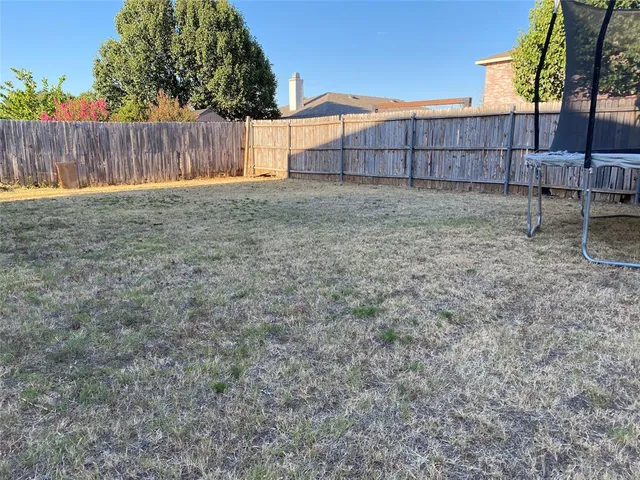 a view of a backyard with a fence and trees