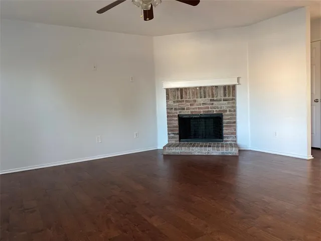 an empty room with wooden floor fireplace and windows