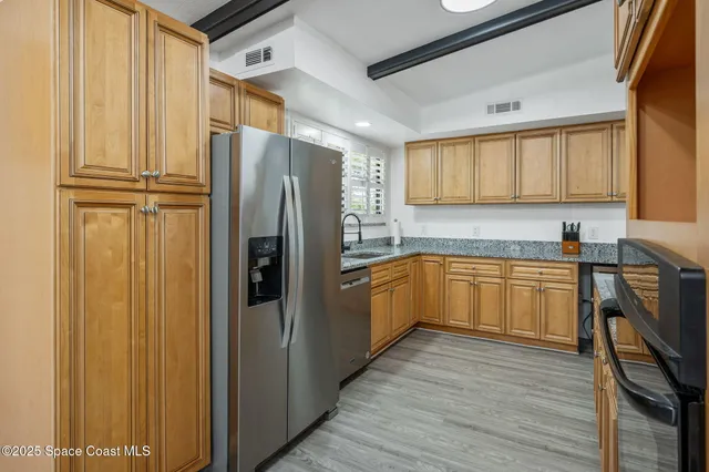 a kitchen with a refrigerator a sink and dishwasher with wooden floor