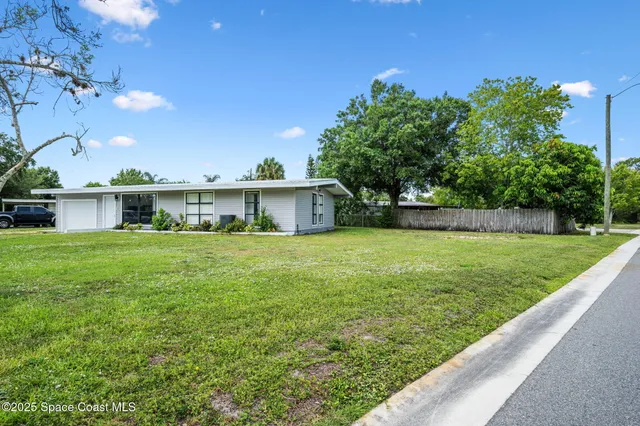 a front view of house with yard and trees in the background