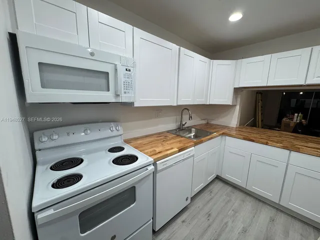 a kitchen with granite countertop white cabinets and white stove