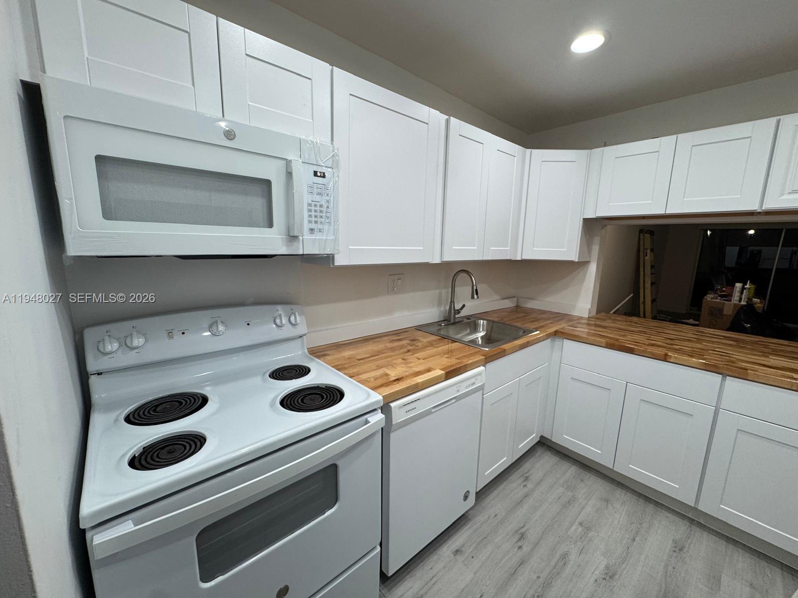 a kitchen with granite countertop white cabinets and white stove