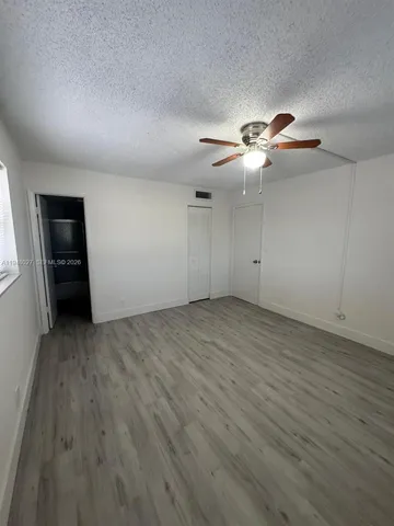 an empty room with wooden floor chandelier fan and windows