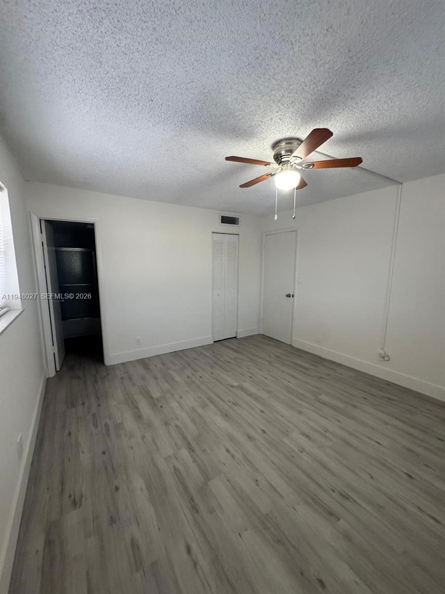 8051 South Colony Circle, Unit 210 Tamarac, FL 33321 - Photo 7 of 25 an empty room with wooden floor chandelier fan and windows