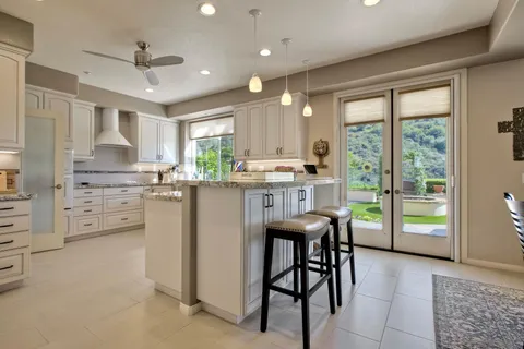 a kitchen with stainless steel appliances granite countertop a stove a sink dishwasher a refrigerator and white cabinets with wooden floor