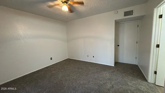 an empty room with a ceiling fan and closet area