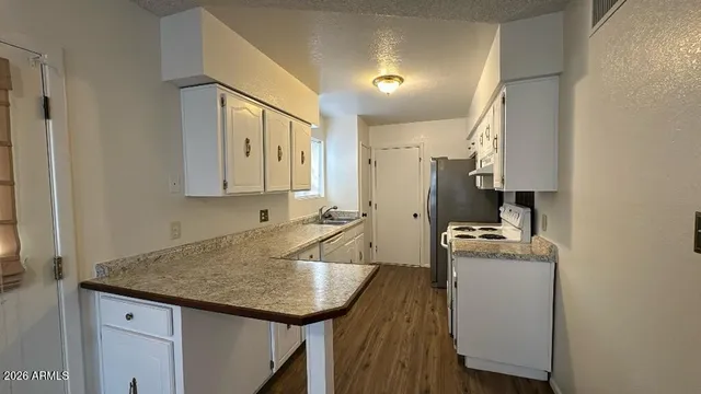 a kitchen with granite countertop a sink a stove and cabinets