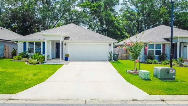 a front view of a house with a yard and potted plants