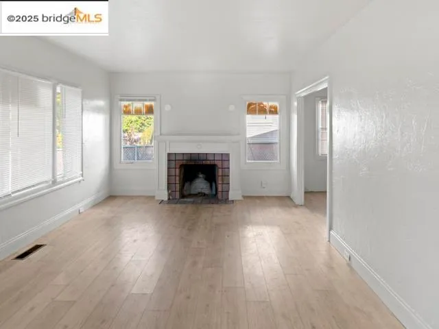 a view of empty room with wooden floor and fireplace