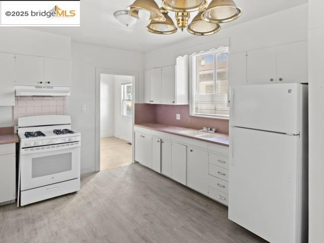 1556 78th Avenue Oakland, CA 94621 - Photo 5 of 11 a kitchen with cabinets stainless steel appliances and wooden floor