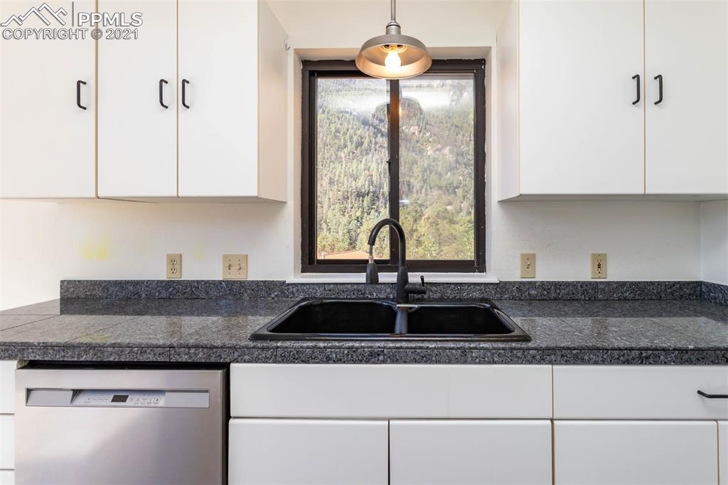 4440 Prairie Street Cascade, CO 80809 - Photo 33 of 38 a kitchen with granite countertop a sink and white cabinets
