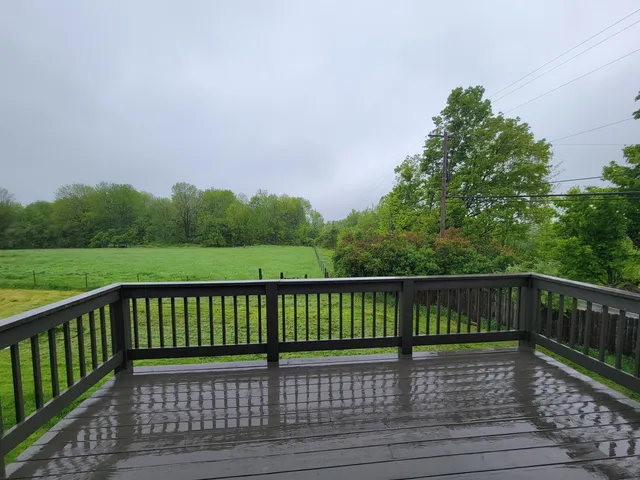 a view of deck with wooden floor and fence next to a yard