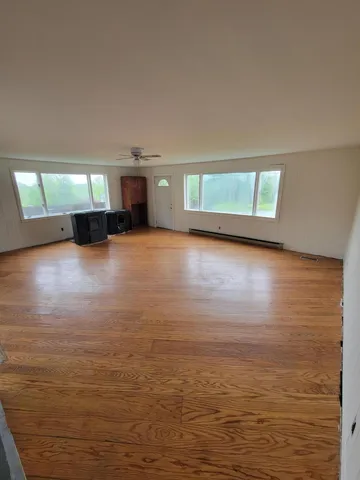 a view of empty room with kitchen and window
