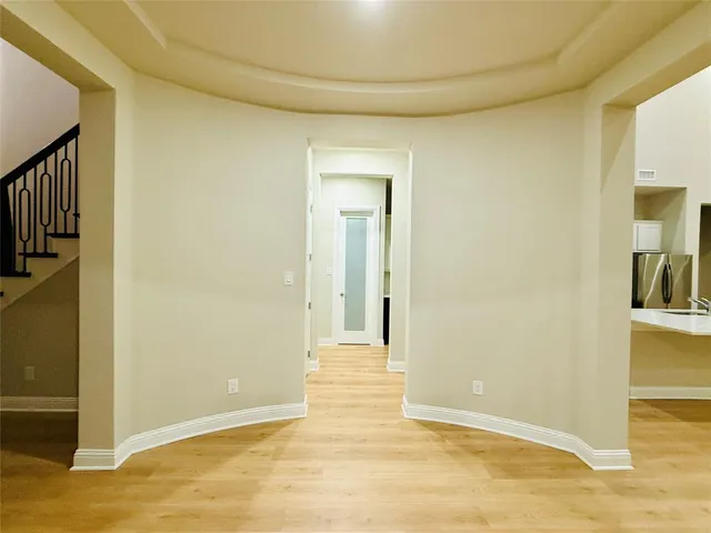 a view of an empty room with wooden floor and windows
