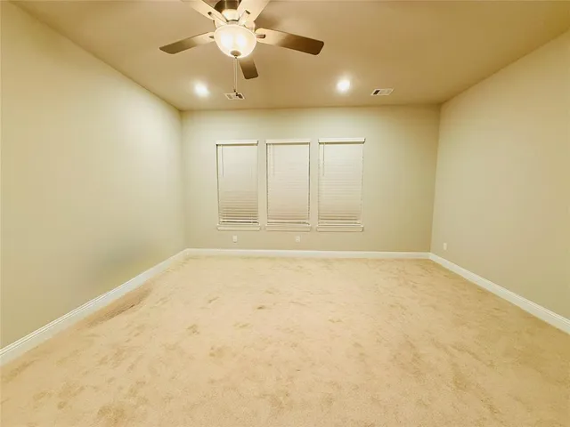 an empty room with a ceiling fan and window