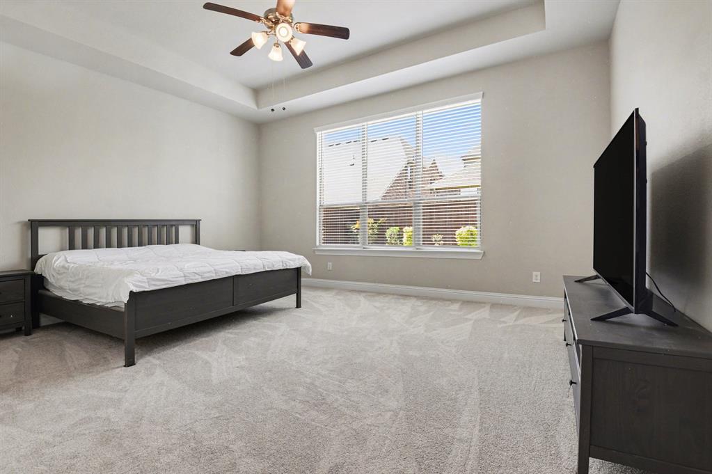 3323 Royal Ridge Drive Rockwall, TX 75087 - Photo 14 of 37 a spacious bedroom with a bed table and flat screen tv