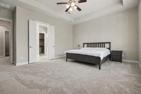 a spacious bedroom with a bed and ceiling fan