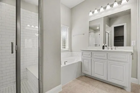 a bathroom with a double vanity sink mirror and bathtub