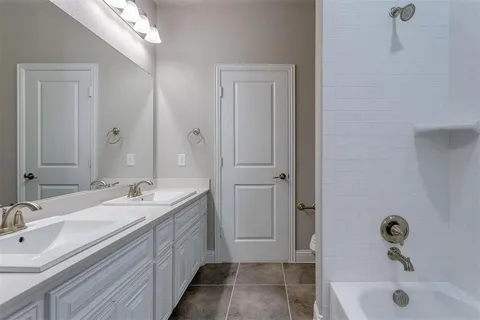 a bathroom with a double vanity sink a mirror and a bathtub