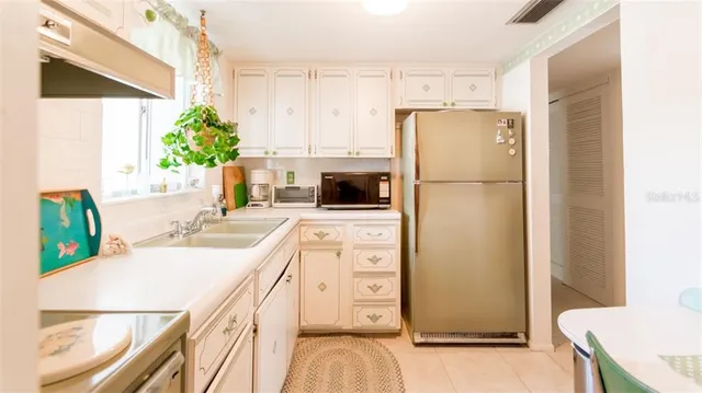 a kitchen with a refrigerator a stove a sink a counter space and wooden floor