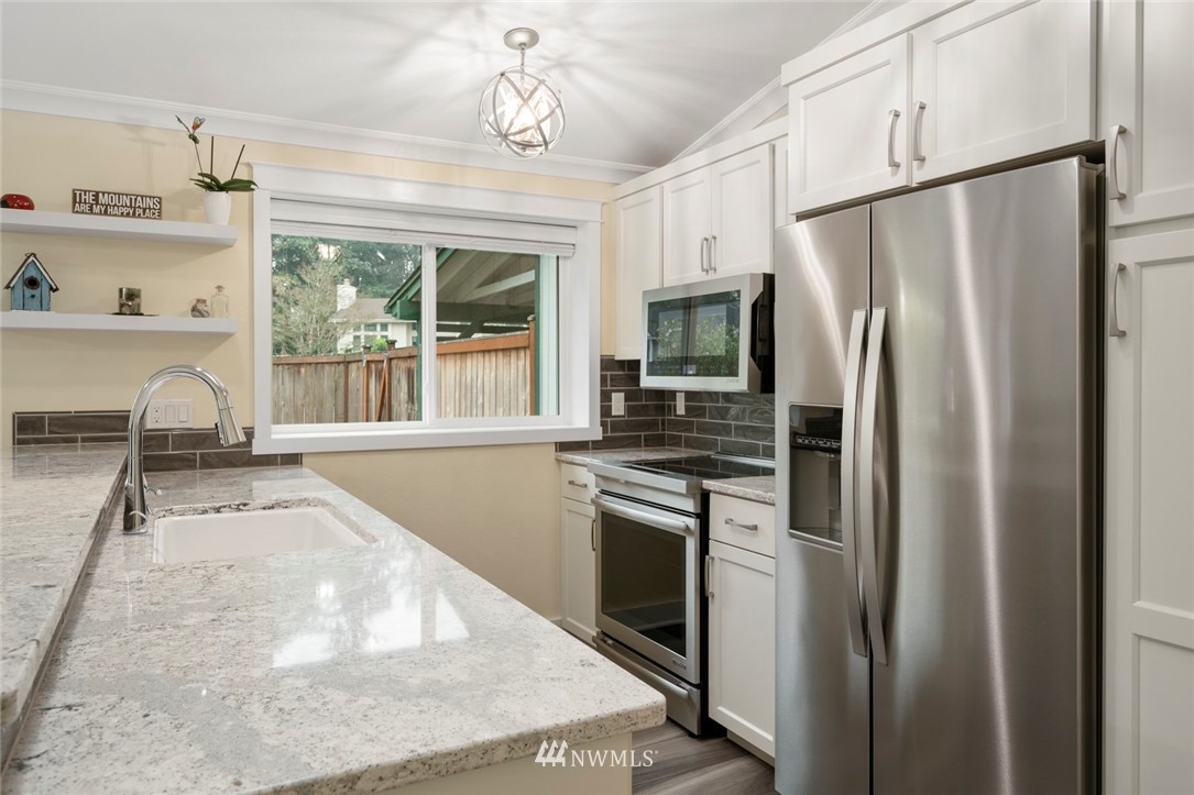 23513 22nd Avenue Southeast Bothell, WA 98021 - Photo 19 of 33 a kitchen with stainless steel appliances granite countertop a refrigerator a stove and a sink with large window