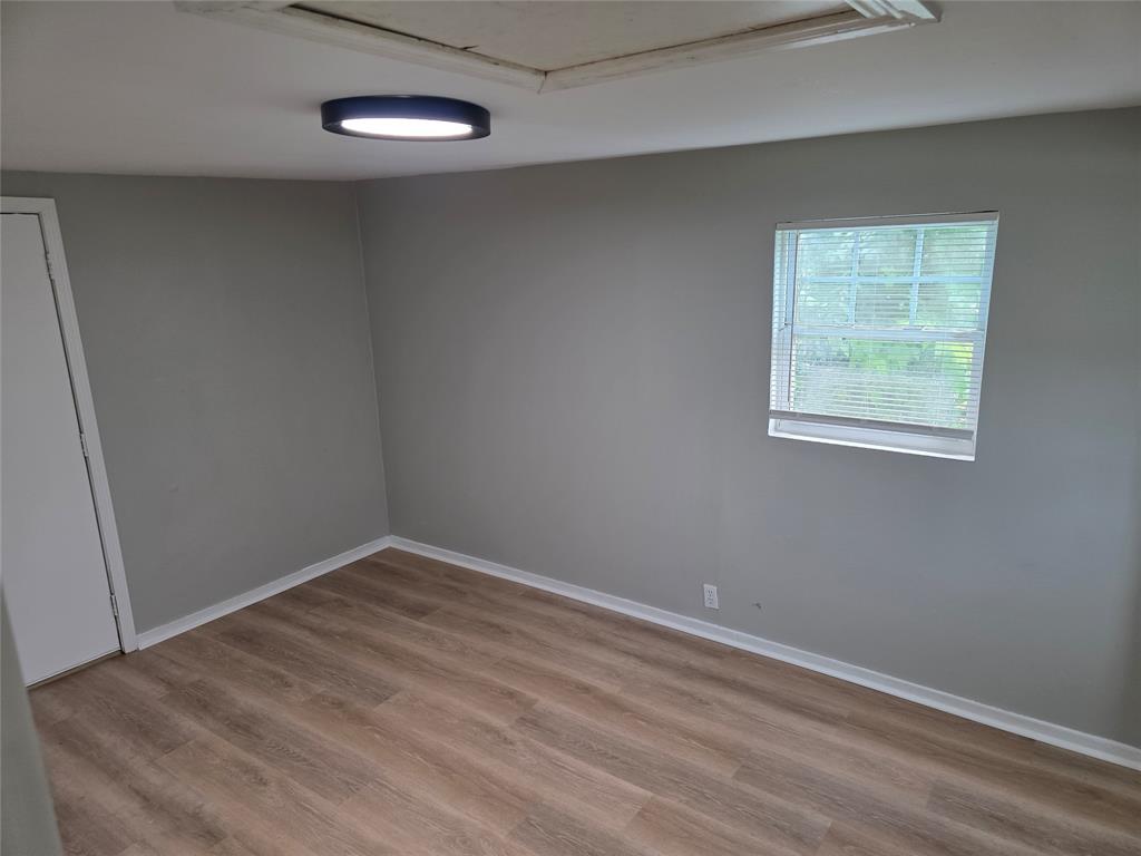 2804 Summer Avenue Waco, TX 76708 - Photo 12 of 13 Room featuring wood-finish flooring, neutral gray walls, a window with blinds, and an overhead flush-mount light fixture