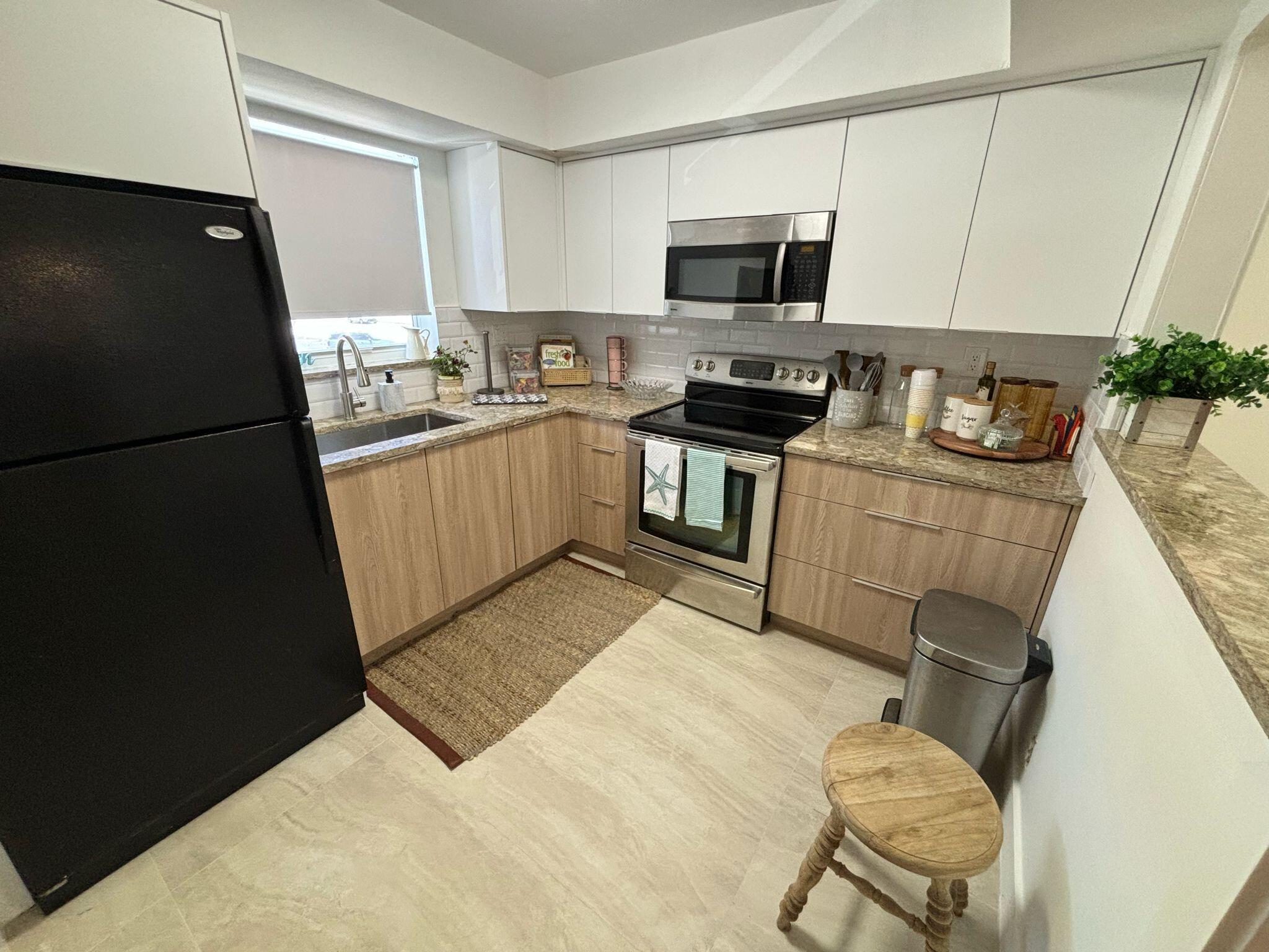 1150 East Sample Road Pompano Beach, FL 33064 - Photo 7 of 12 a kitchen with stainless steel appliances a refrigerator sink stove microwave and cabinets