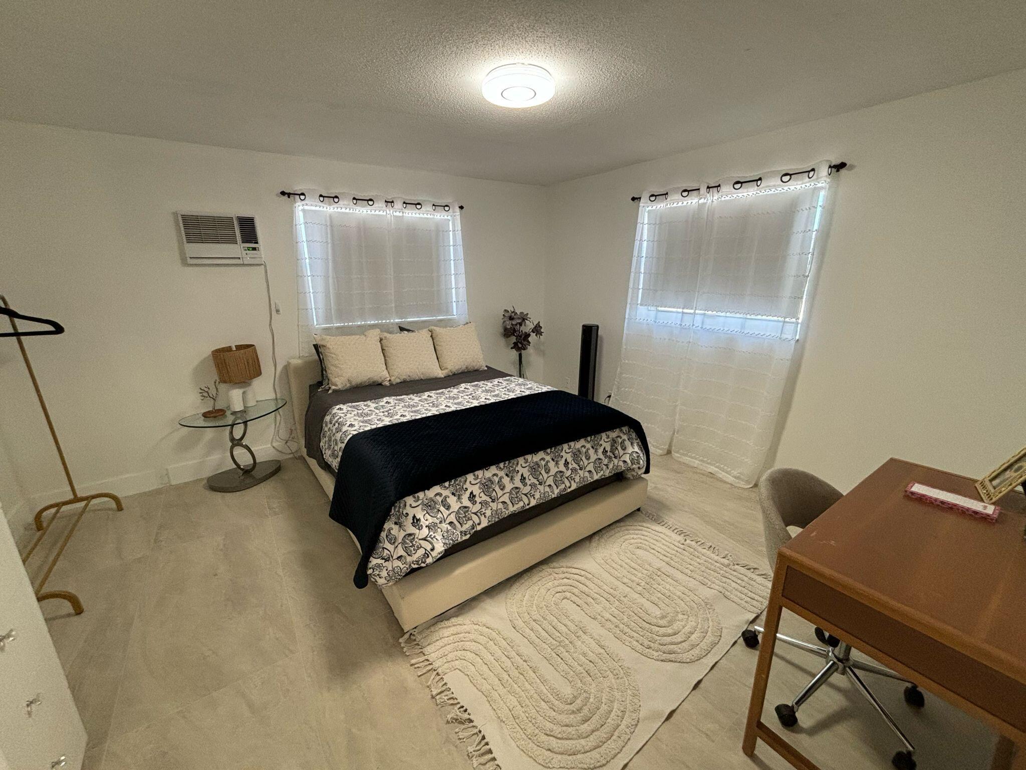 1150 East Sample Road Pompano Beach, FL 33064 - Photo 8 of 12 a bedroom with a bed and a table in it